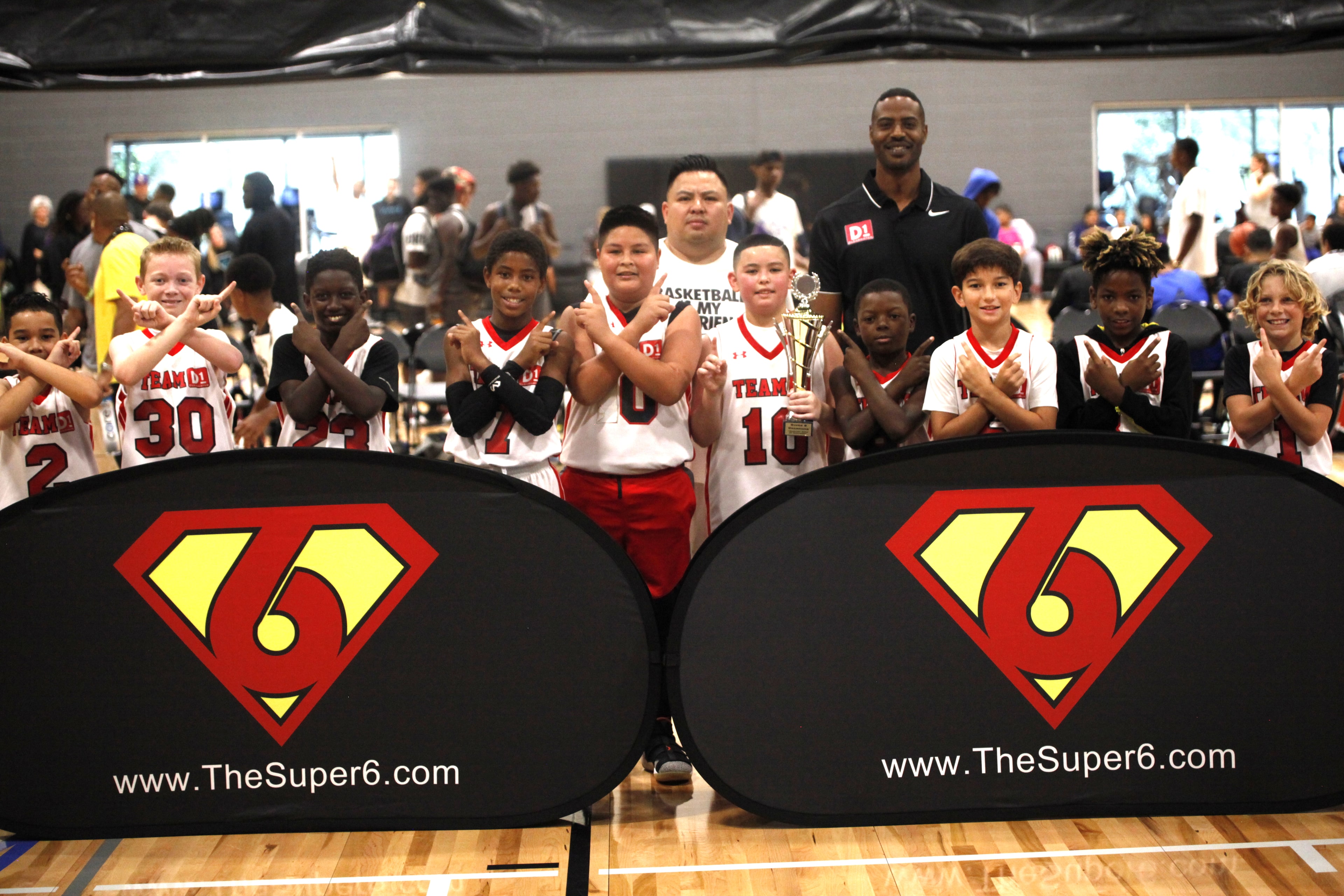 Youth champions holding trophy in front of Super6 banners