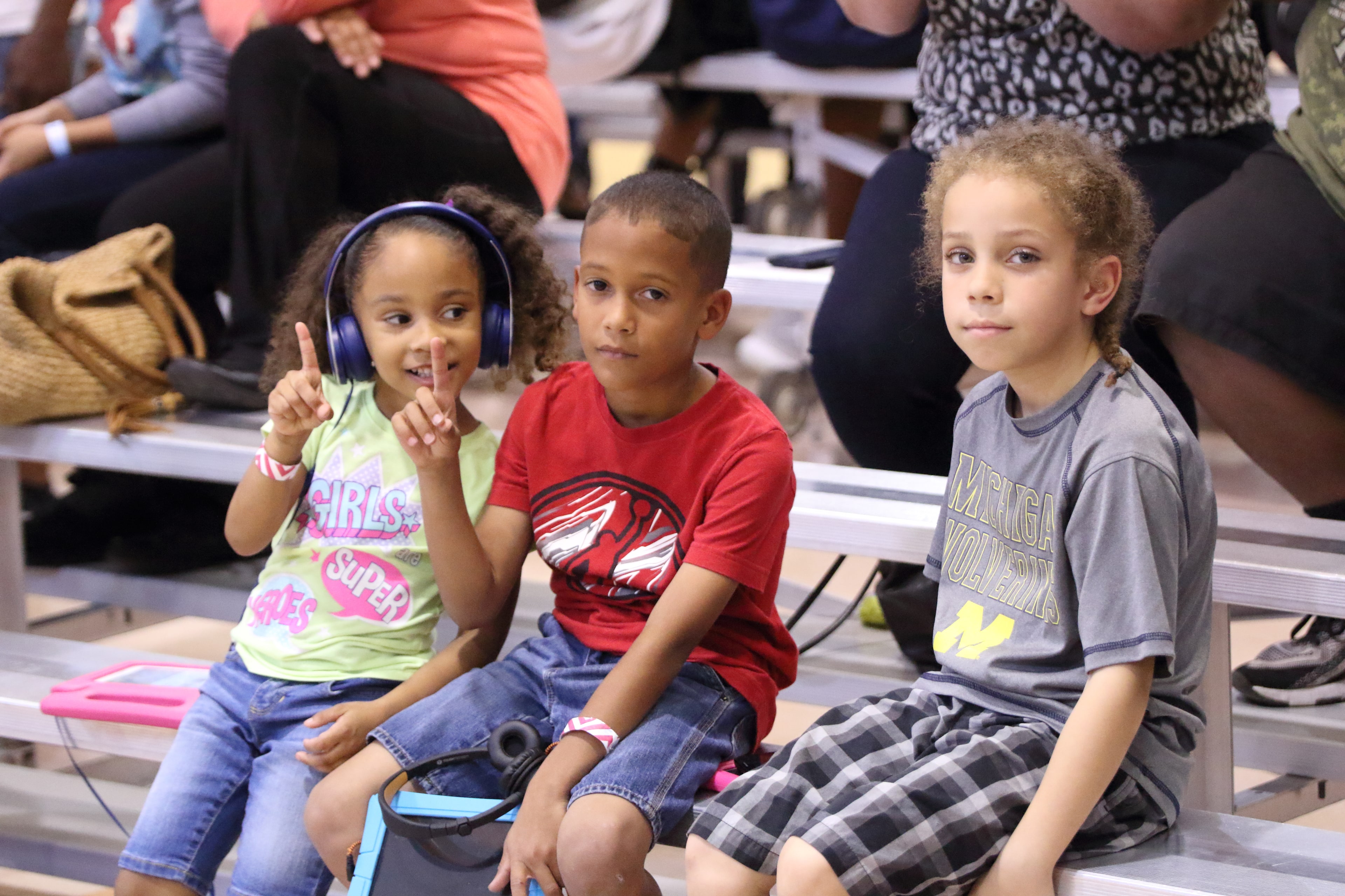 Three young fans in the stands wearing Super6 gear